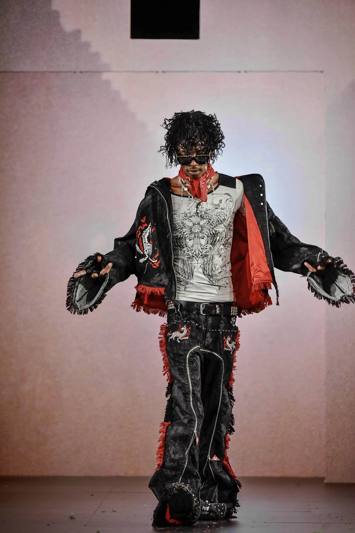 The black waxed denim jacket held open on the New York runway, showing the red satin lining